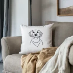 A sad puppy embroidered throw pillow on the sofa, with some scattered clothes beside it.
