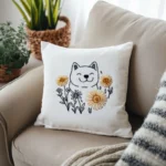 A throw pillow with an embroidered Shiba Inu and dandelion, placed on a sofa.
