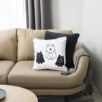 One Smiling white and two black Samoyeds embroidered on a cushion.