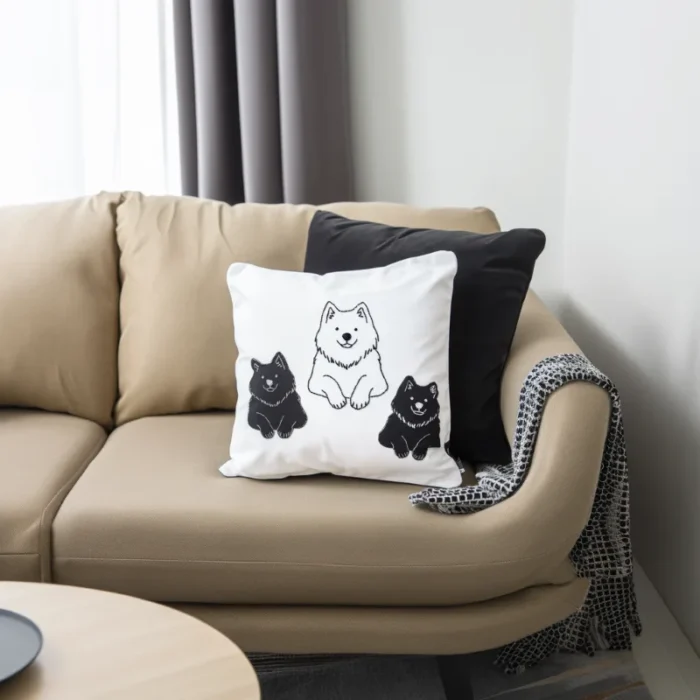 One Smiling white and two black Samoyeds embroidered on a cushion.