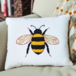 A cozy sofa with a decorative pillow embroidered with an adorable bee design