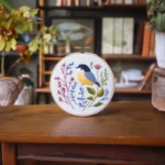 A rustic table displaying a vibrant spring-themed embroidery artwork