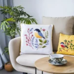 A sofa with assorted pillows in various sizes and colors, with a coffee table in front holding a cup of coffee