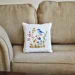 A vintage-style sofa featuring a white bird and floral embroidered pillow