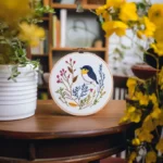 An embroidered bird design alongside vibrant yellow flowers in the scene
