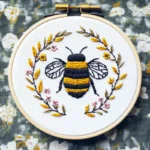 Bee embroidery artwork centered in a floral wreath