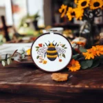 Bee-themed embroidery pattern placed on a table with sunflowers as decoration