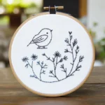 Close-up of a minimalist bird and branch embroidery artwork