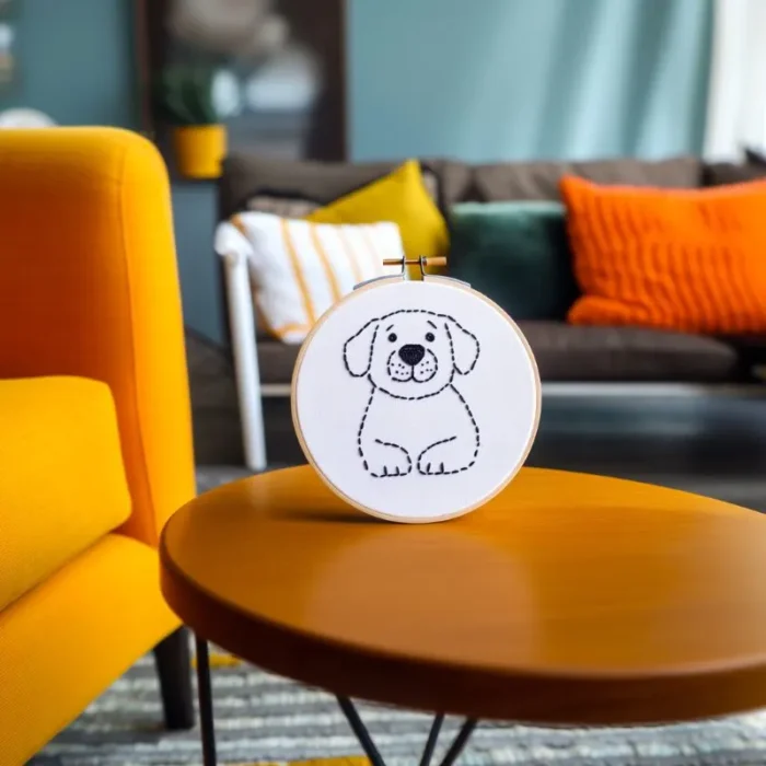 Minimalist black-and-white Labrador embroidery artwork displayed in a lively, colorful space