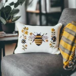 Rectangular embroidered pillow and folded blanket placed on a soft chair