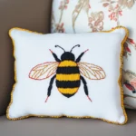Throw pillow featuring an embroidered bee with open wings