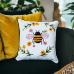 Yellow pillow and white pillow with bee embroidery on a black sofa
