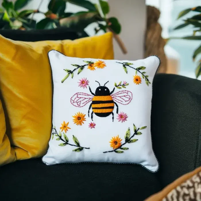 Yellow pillow and white pillow with bee embroidery on a black sofa