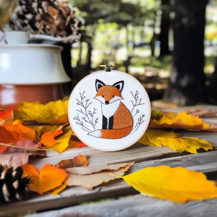 A small fox handmade embroidery placed on a wooden bench in a park
