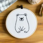 Close-up of cute bear sitting on the ground embroidery artwork