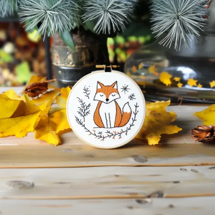Fox embroidery artwork with yellow leaves and a small potted plant