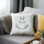 Gray sofa with a white fabric pillow featuring black line rabbit embroidery