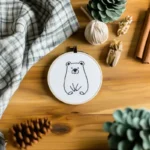 Minimalist line bear embroidery displayed on a table with decorative items enhancing the atmosphere