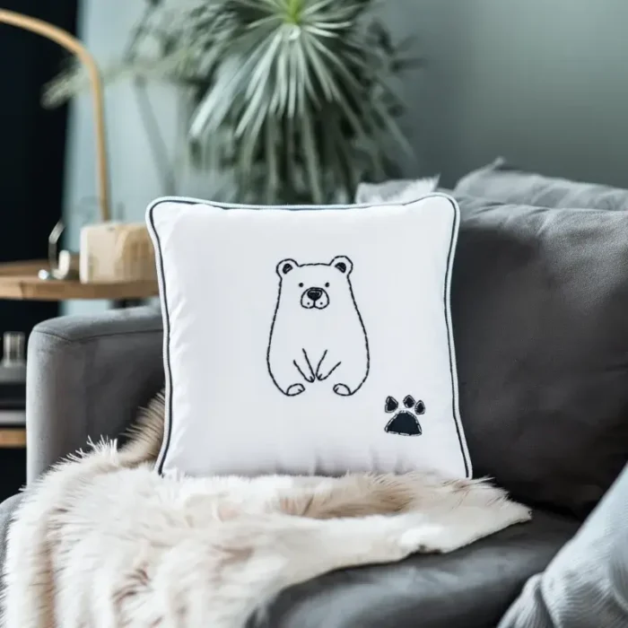 Minimalist line bear embroidery pillow placed on a fluffy blanket