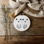 Hand embroidery artwork with decorative dry branches and white fabric on a table