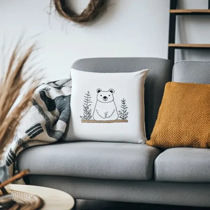 Gray fabric sofa with a white bear embroidery pillow and an earthy yellow cushion