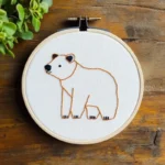 Handmade bear embroidery artwork placed on a table, showing a bear strolling peacefully