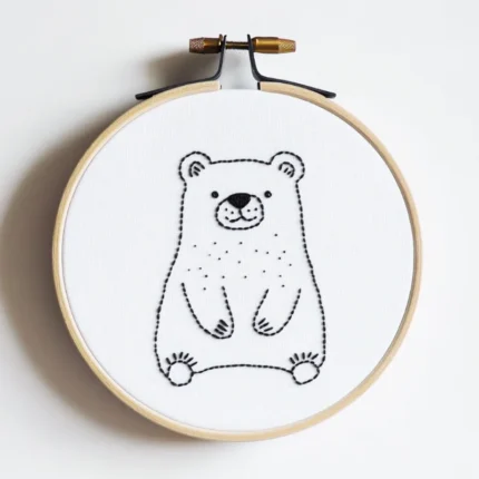 Handmade bear embroidery in a hoop on white fabric, featuring a gentle bear quietly gazing forward