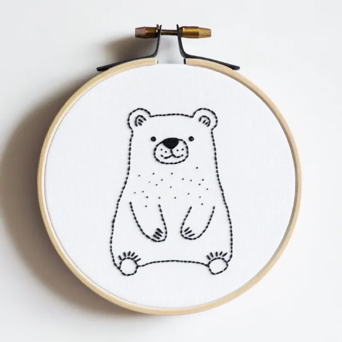 Handmade bear embroidery in a hoop on white fabric, featuring a gentle bear quietly gazing forward