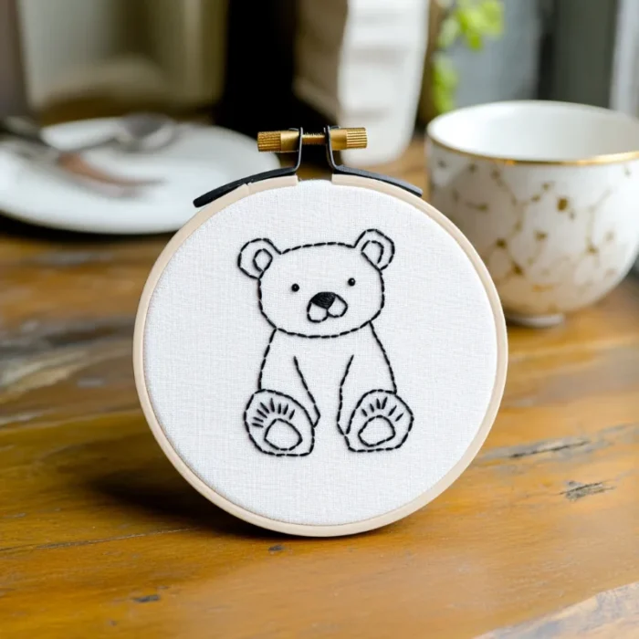 Handmade embroidery of a cute, chubby bear displayed on a tabletop