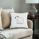 Khaki-colored sofa with a gold-trimmed embroidery pillow featuring a bear outlined in golden thread