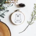 Peaceful handmade bear embroidery displayed with wooden branches and natural elements