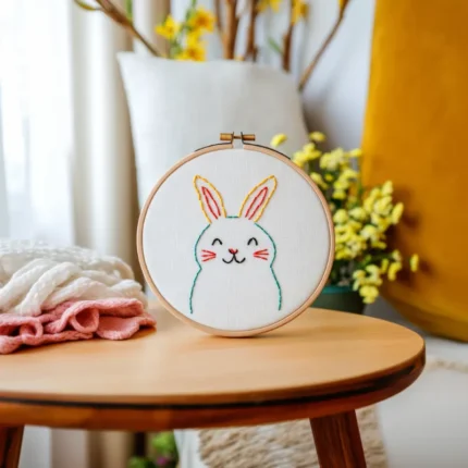 Bright and cozy living room with a small table featuring a rabbit embroidery artwork and knitted fabric