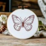 brick-red butterfly embroidery displayed in an embroidery hoop