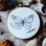 butterfly embroidery artwork with simple geometric lines on table