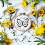 butterfly embroidery on white fabric with small yellow flowers as decoration