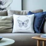 gray sofa with gray cushion, blue cushion, and white cushion embroidered with butterfly design