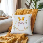 gray sofa with orange knitted throw and white fabric rabbit embroidery cushion