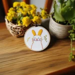 hand-embroidered rabbit on table with decorative artificial flowers