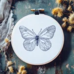 modern butterfly embroidery in deep blue minimalist lines displayed on a blue tabletop