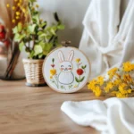 Rabbit embroidery on breathable white fabric with decorative flowers on table