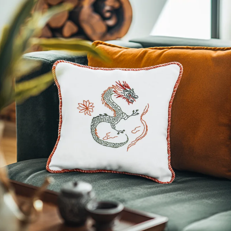 Green sofa with two pillows, one in orange and the other in white Green sofa with two pillows, one in orange and the other a white embroidered pillow featuring a dragon