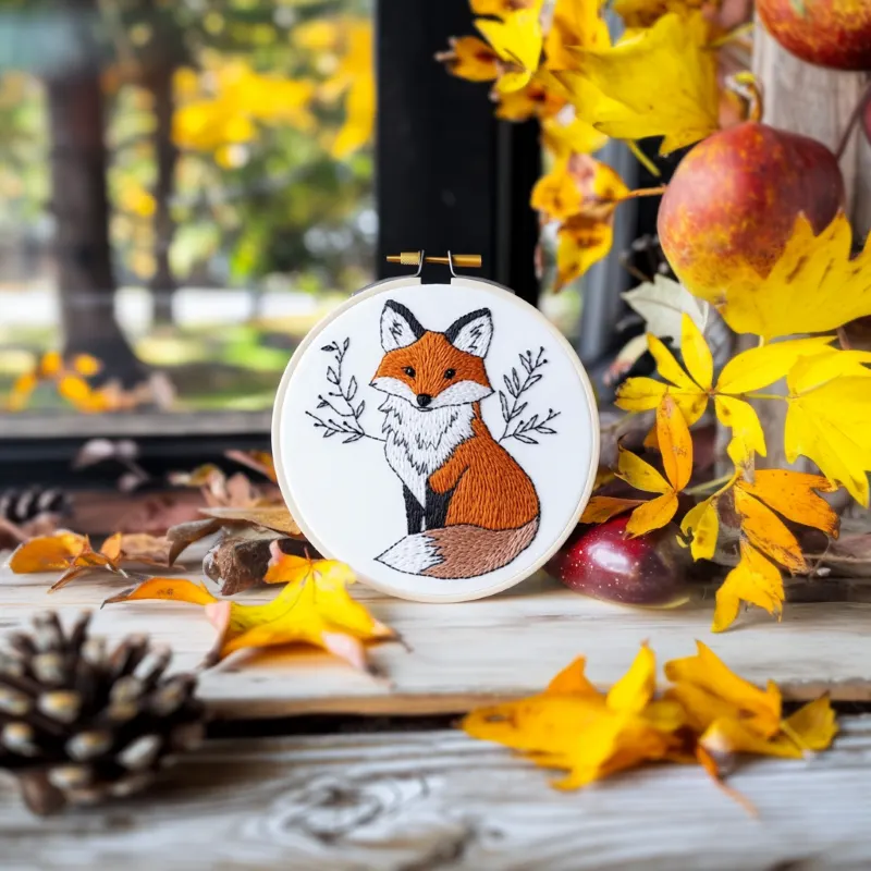 delicate fox embroidery piece displayed on the floor with pinecones and leaves delicate fox embroidery piece displayed on the floor with pinecones and leaves