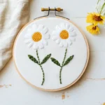 delicate handmade embroidery on a table featuring two daisy flowers