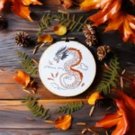 dragon hand embroidery design in a hoop with clouds, decorated with scattered leaves