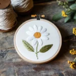 embroidery hoop with fabric on the floor featuring a beautiful daisy flower design