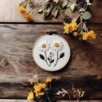 embroidery hoop with three daisy flowers, decorated with fresh yellow wildflowers