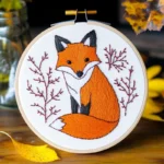 finished hand embroidery of a cute fox with tree branches in a hoop