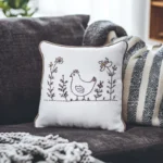 gray sofa with a blanket and a cushion embroidered with a minimalist design