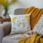 gray sofa with a daisy embroidery cushion and a mustard yellow blanket