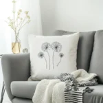 gray sofa with a dandelion embroidered cushion beside a clear glass vase of flowers